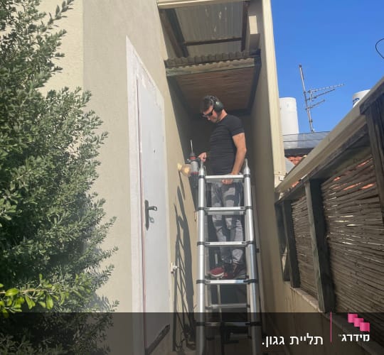 אדם על סולם עובד על תיקון חיצוני של מבנה